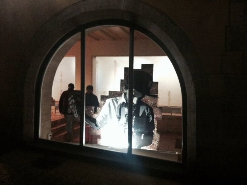 Blick durch ein Rundbogenfenster auf Menschen in einem hell erleuchteten Raum