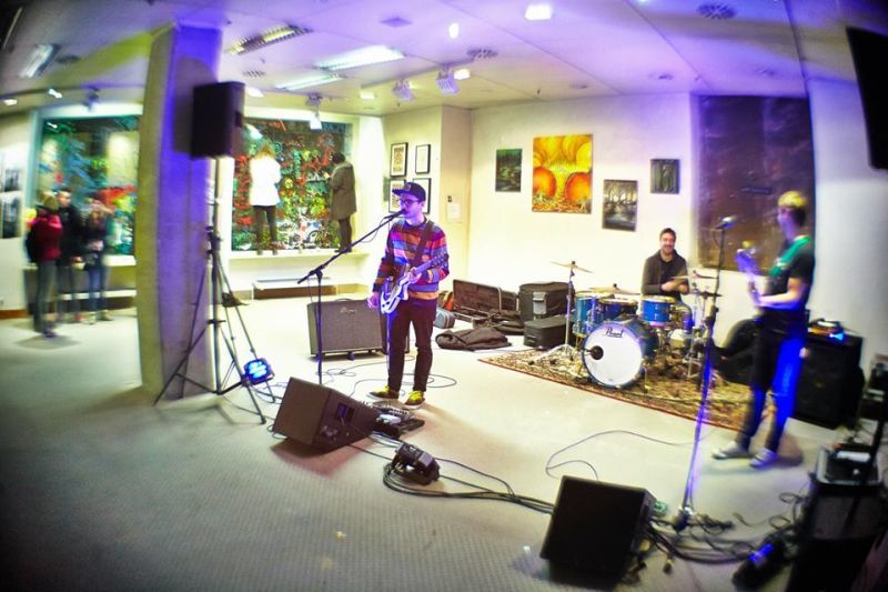 Band spielt in einem Raum, an den Wänden hängt Kunst